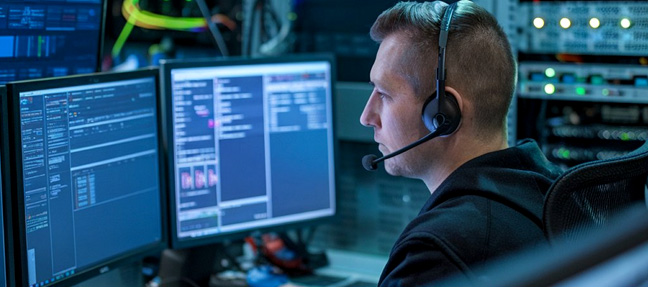 IT operator wearing headset monitoring servers in noc dashboard